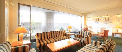 Uma sala de estar espaçosa com sofás listrados, uma mesa de centro de madeira e uma grande janela com vista para o exterior.