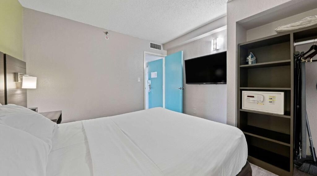 Habitación de hotel con cama, televisión, armario y panel de control.