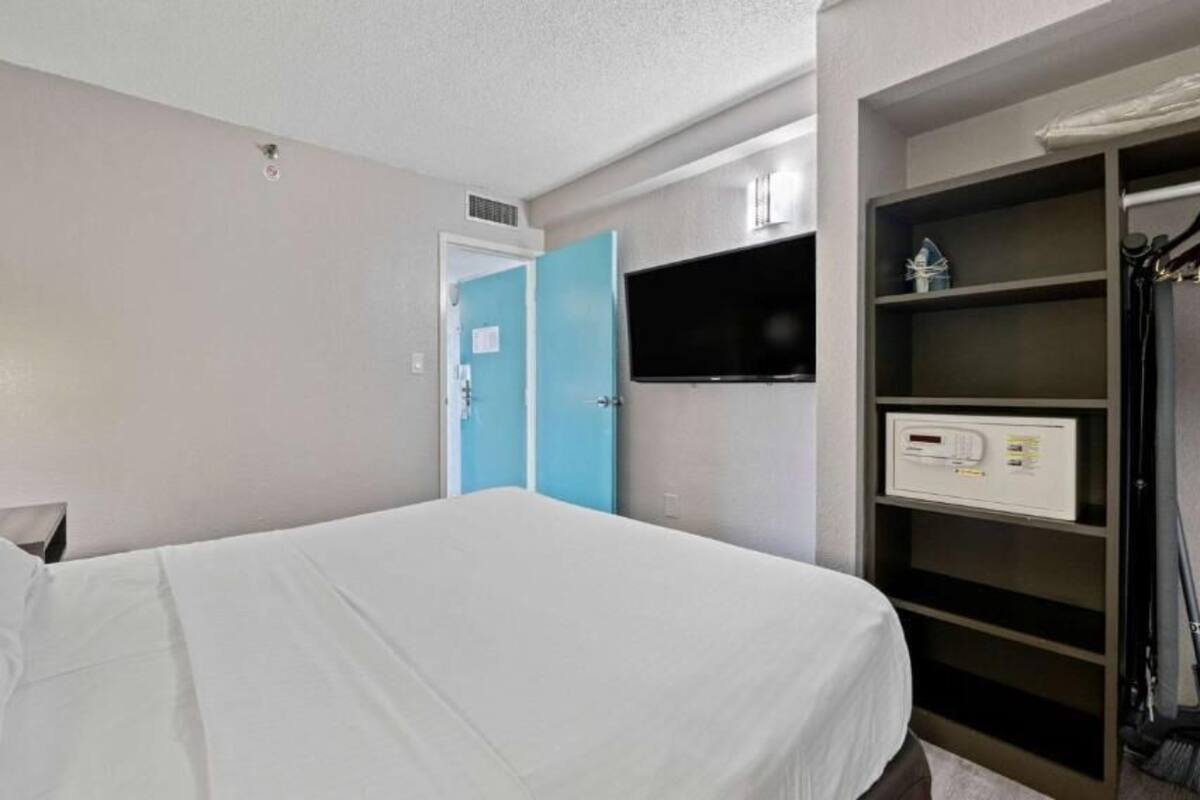 Ein Hotelzimmer mit einem Bett, einem Fernseher, einem Kleiderschrank und einer Bedienkonsole.