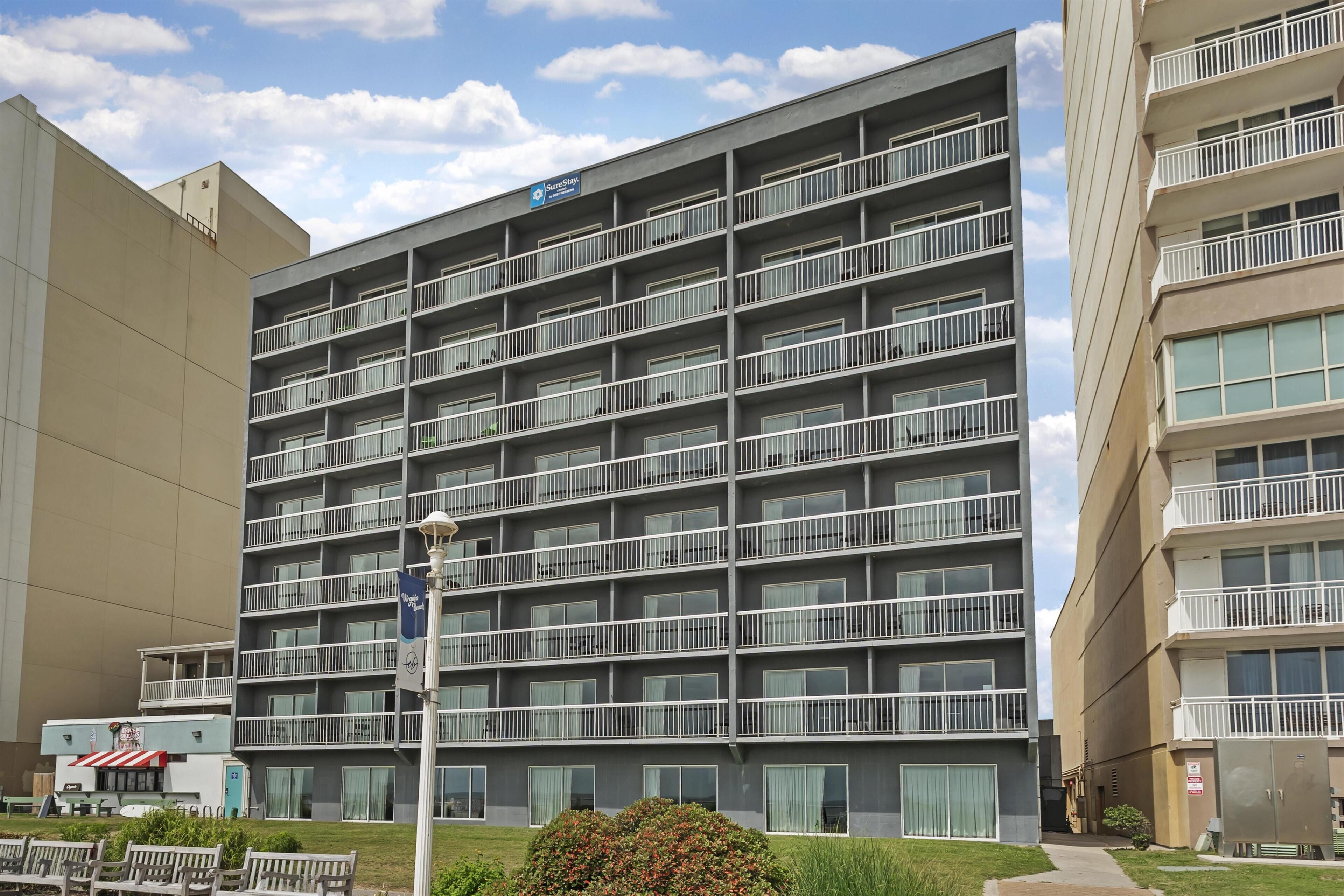 A multi-story hotel with balconies, a sign indicating it is a Sun-Stop hotel, and a small outdoor seating area.