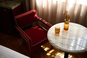 Una silla roja y una mesa redonda con una vela.