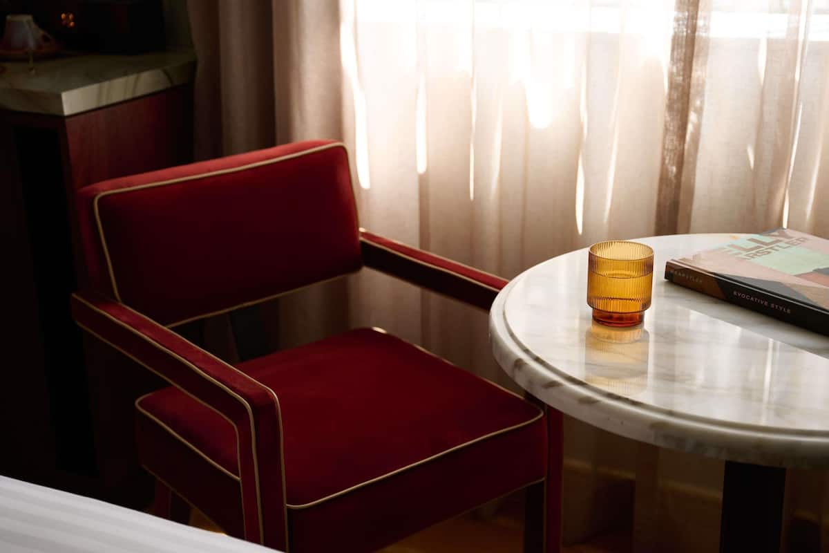 A red upholstered chair, a round table with a glass, and a book titled 'EVOCATIVE STYLE' by WEARSTLER.