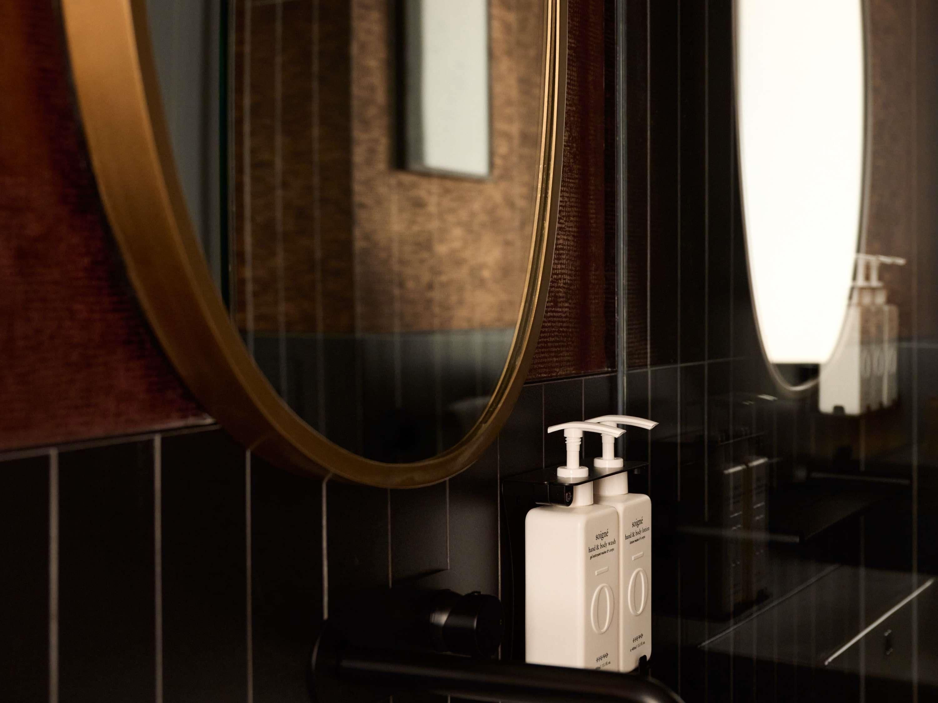 A bathroom with a mirror, a hand soap dispenser, and a towel rack.