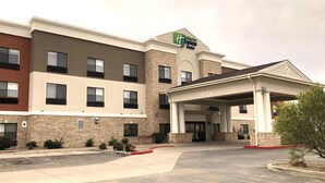 A Holiday Inn Express hotel with a covered entrance, parking lot, and a brick facade. - Holiday Inn Express Hotel & Suites Las Vegas by IHG (Las Vegas)