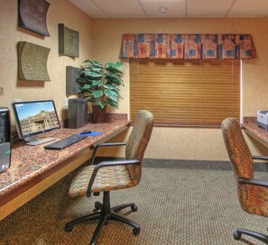 A conference room with a desk, two chairs, a computer, a plant, and a window with blinds. - Holiday Inn Express Hotel & Suites Las Vegas by IHG (Las Vegas)