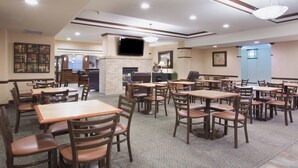 A restaurant with multiple tables and chairs, a flat-screen TV mounted on the wall, and a fireplace. - Holiday Inn Express Hotel & Suites Las Vegas by IHG (Las Vegas)