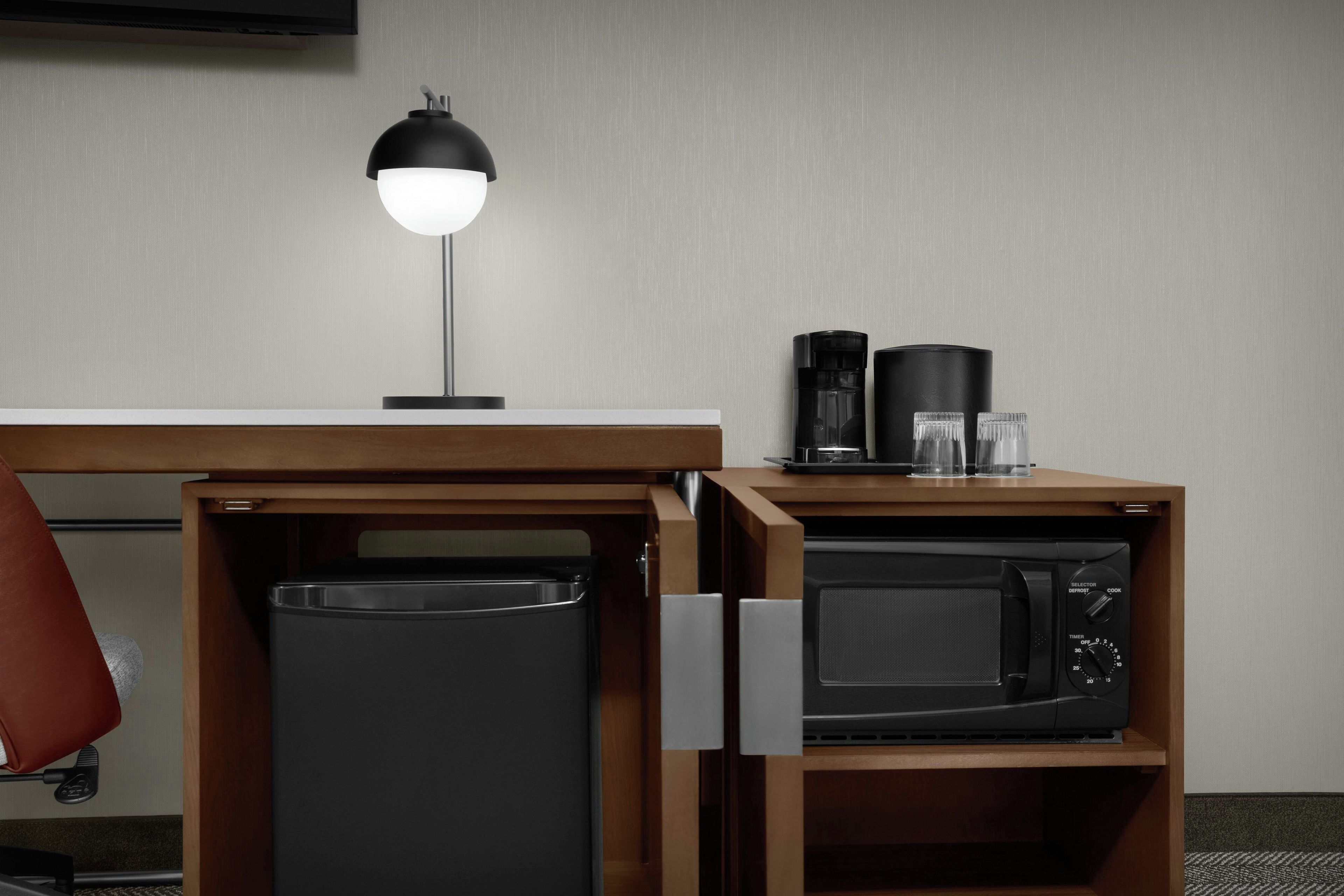 A compact kitchenette with a microwave, a coffee maker, and a small refrigerator.