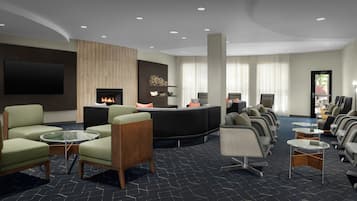 Un hall d’hôtel moderne doté d’une cheminée, d’un coin salon et d’un téléviseur à écran plat fixé au mur.