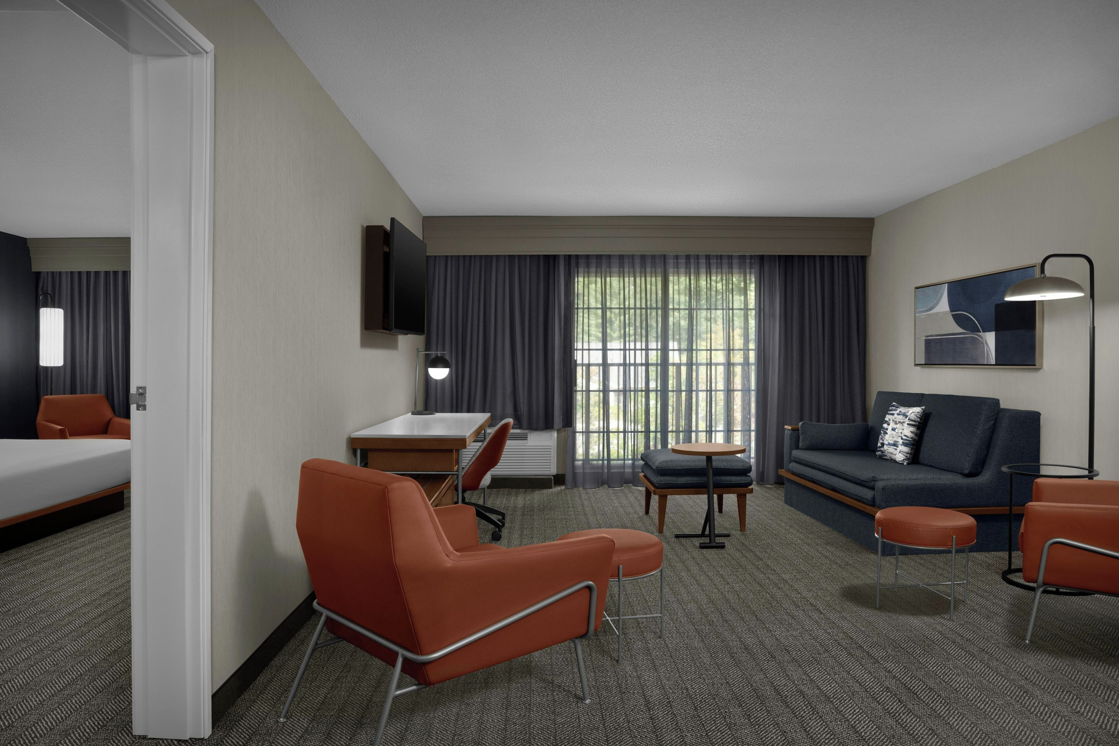 Una habitación de hotel con cama, escritorio, sofá y sillón.
