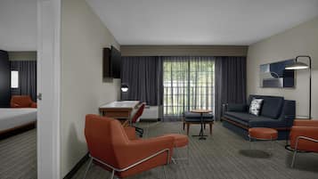 Una habitación de hotel con cama, escritorio, sofá y sillón.