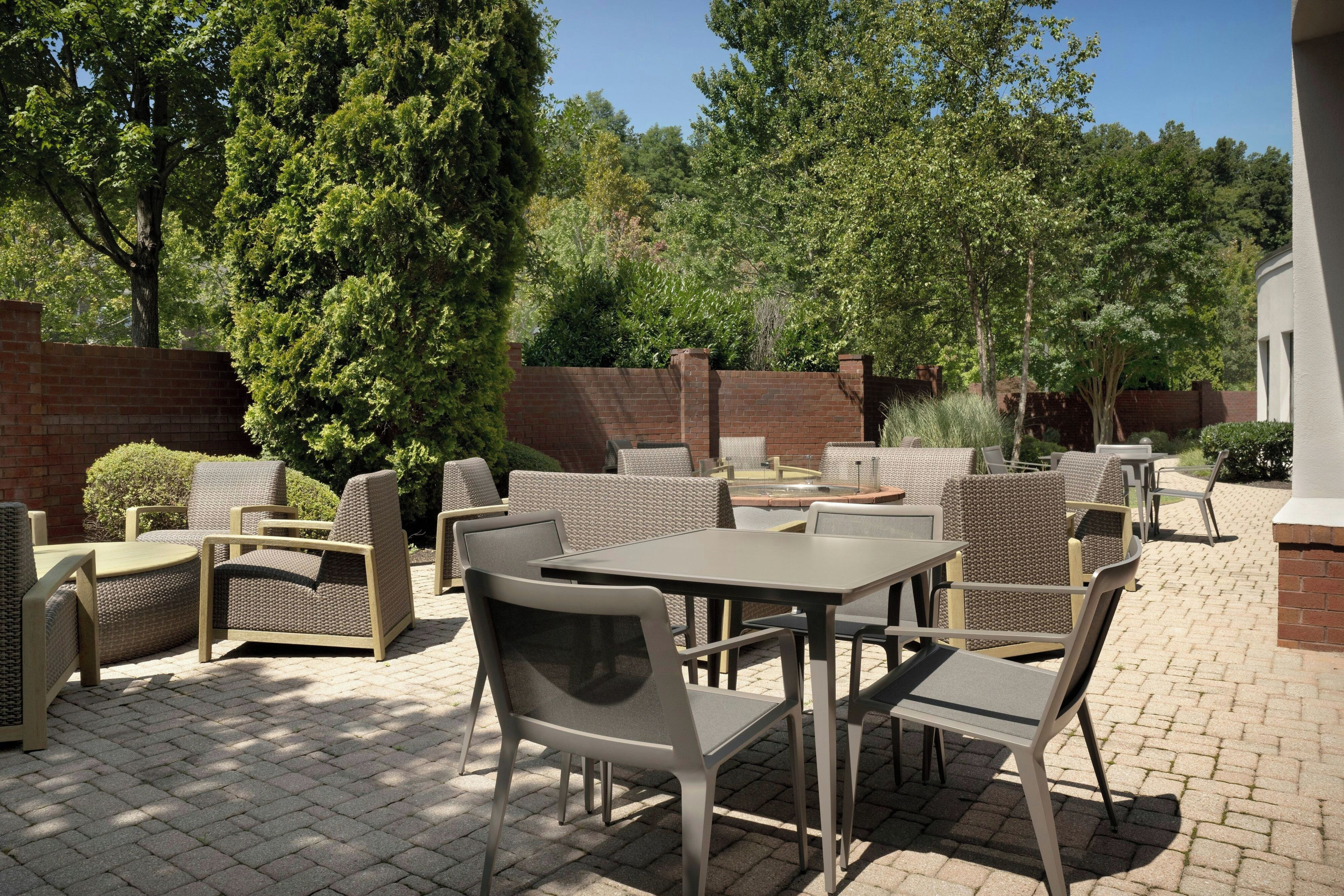 An outdoor patio area with wicker furniture, brick walls, and trees.