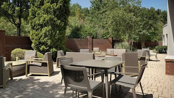 An outdoor patio area with wicker furniture, brick walls, and trees.