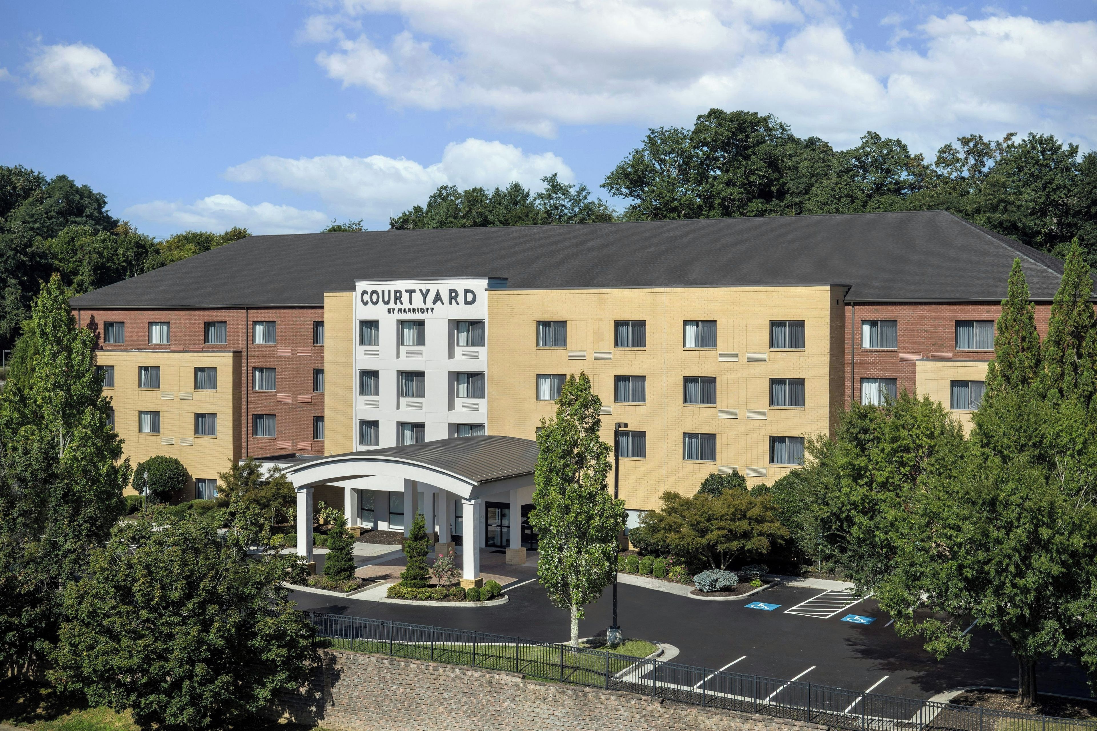 A Courtyard by Marriott hotel with a central courtyard, multiple floors, and a parking lot with handicapped parking spaces.