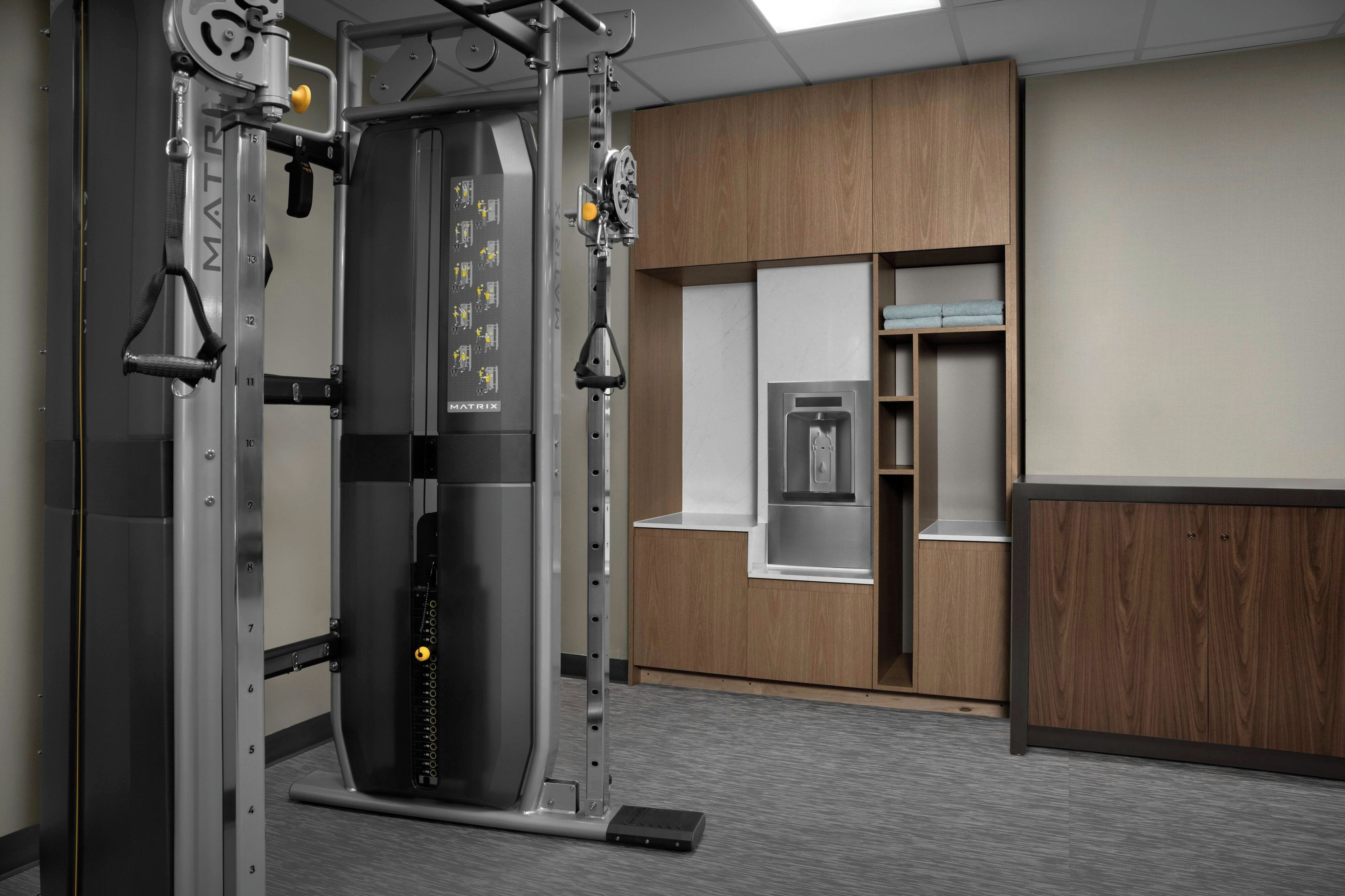 A gym with a weight machine, wooden cabinets, and a water dispenser.
