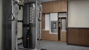 A gym with a weight machine, wooden cabinets, and a water dispenser.