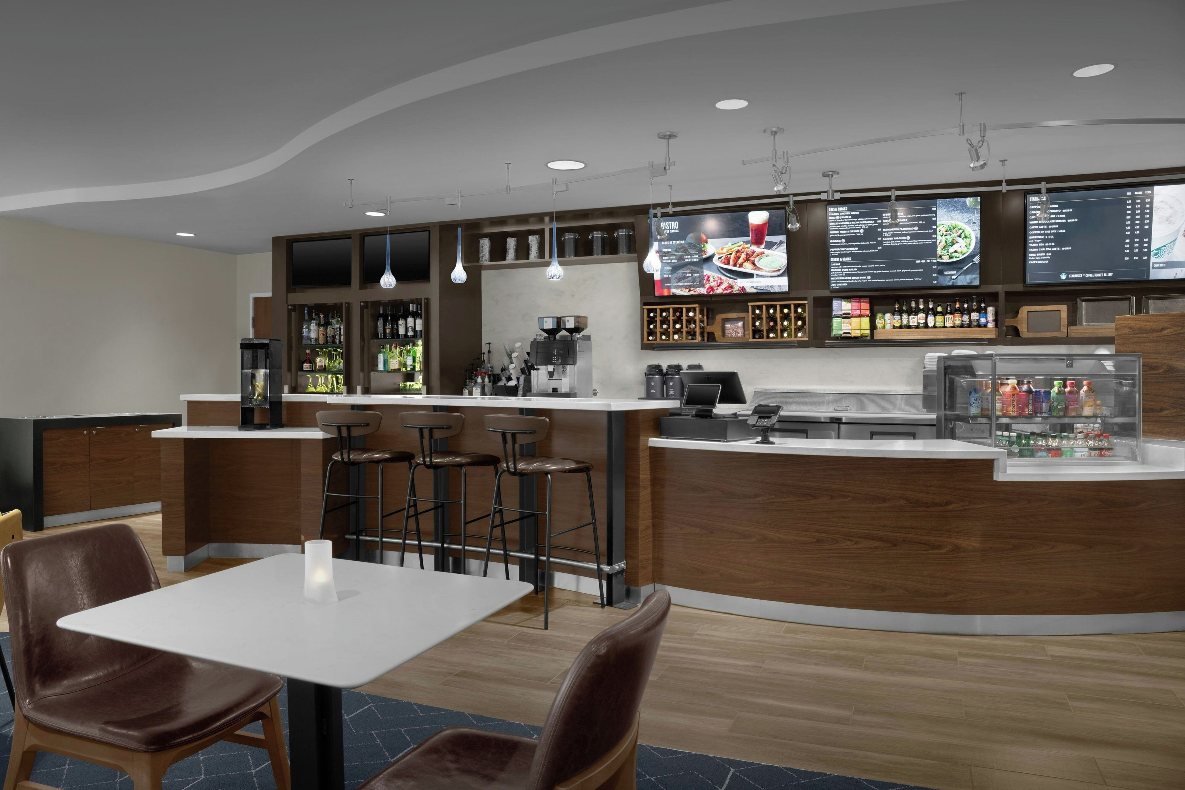 A modern bar area with a counter, stools, and a menu display.