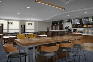 A modern restaurant with a long communal table, bar area, and seating for guests. - Courtyard by Marriott Blacksburg (Blacksburg)