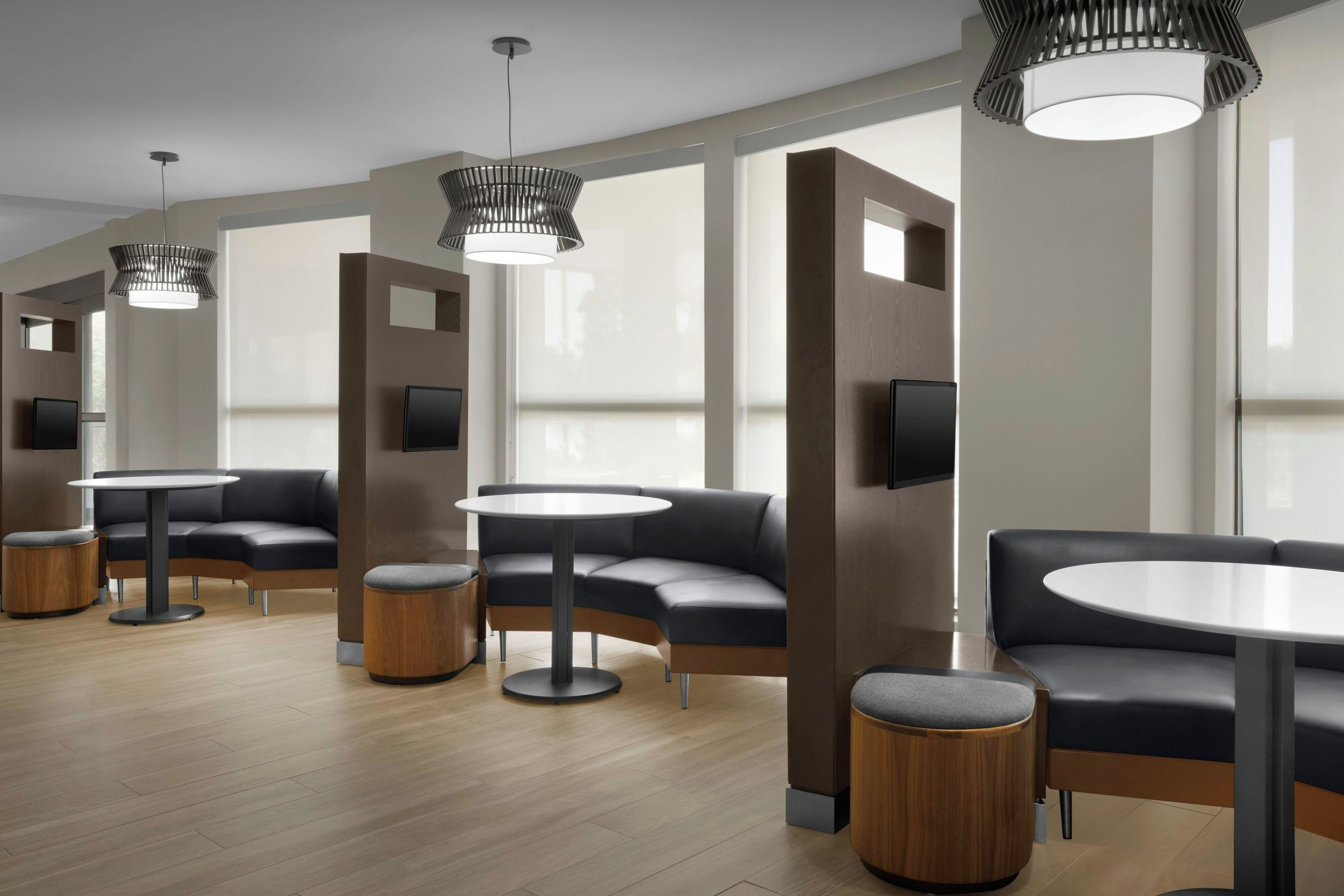 A modern lounge area with round tables, cushioned seating, and pendant lighting.