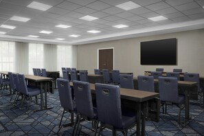 A conference room with tables and chairs, a door, and a projection screen. - Courtyard by Marriott Blacksburg (Blacksburg)