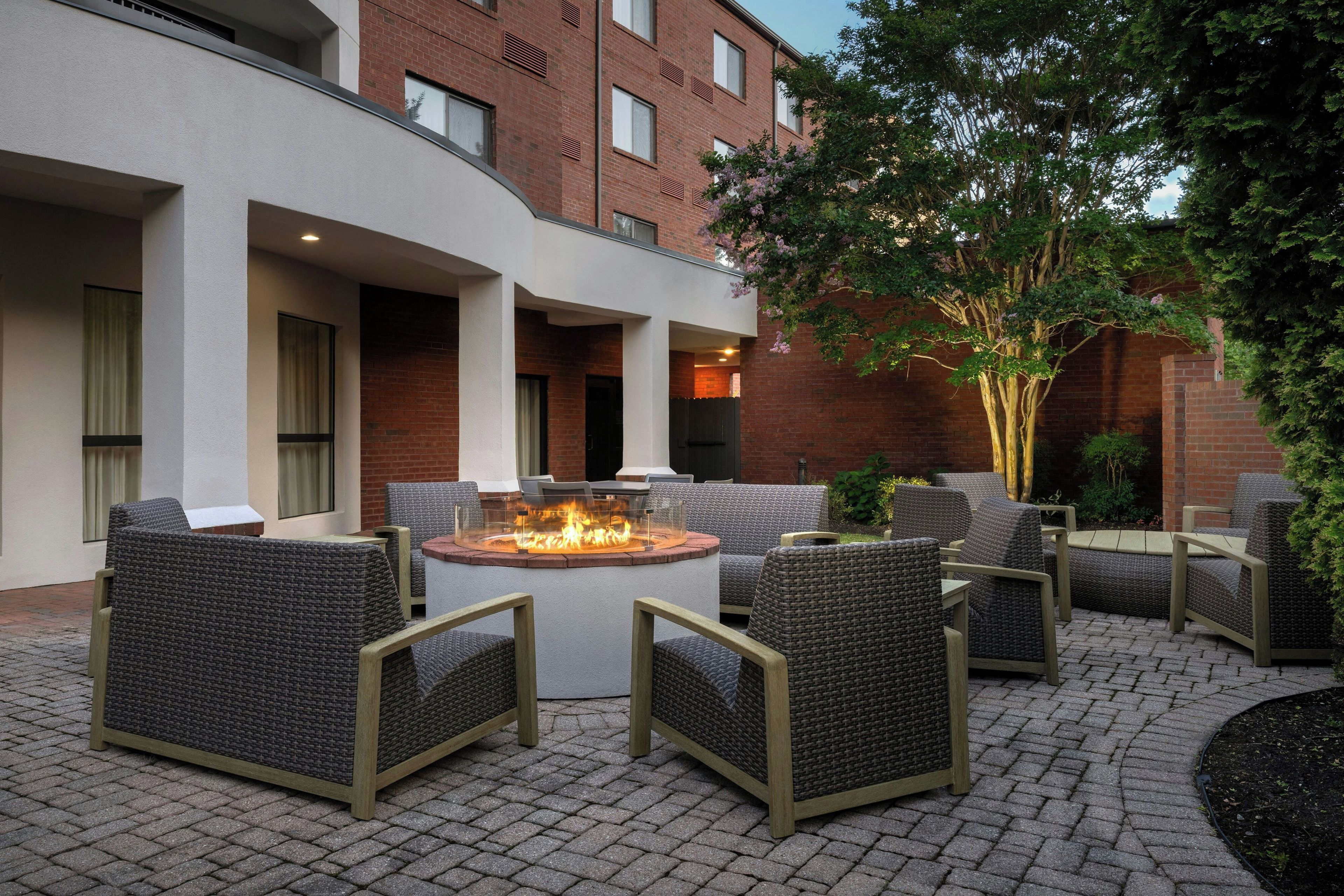 An outdoor patio area with wicker furniture and a central fire feature.