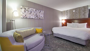 A hotel room with a bed, a sofa, a small table, and a wall-mounted artwork. - Courtyard by Marriott Blacksburg (Blacksburg)