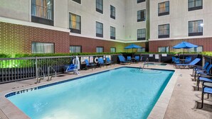 A swimming pool with lounge chairs and umbrellas, surrounded by a brick building with multiple windows. - Homewood Suites Houston West Energy Corridor (Houston)