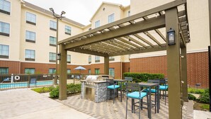 A patio area with a grill, outdoor seating, and a pool. - Homewood Suites Houston West Energy Corridor (Houston)