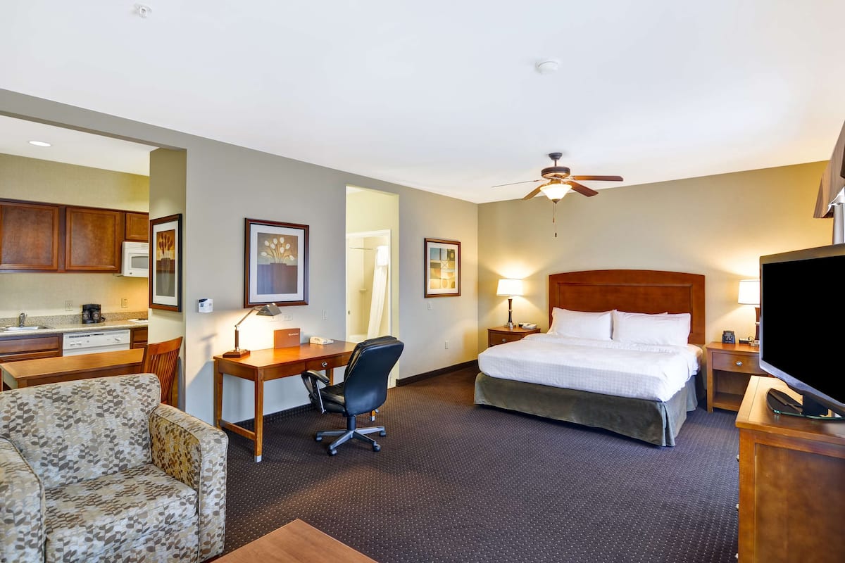 A hotel room with a bed, desk, chair, and a television.