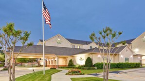A hotel with a flagpole, well-maintained lawn, and a clear sky. - Homewood Suites Houston West Energy Corridor (Houston)