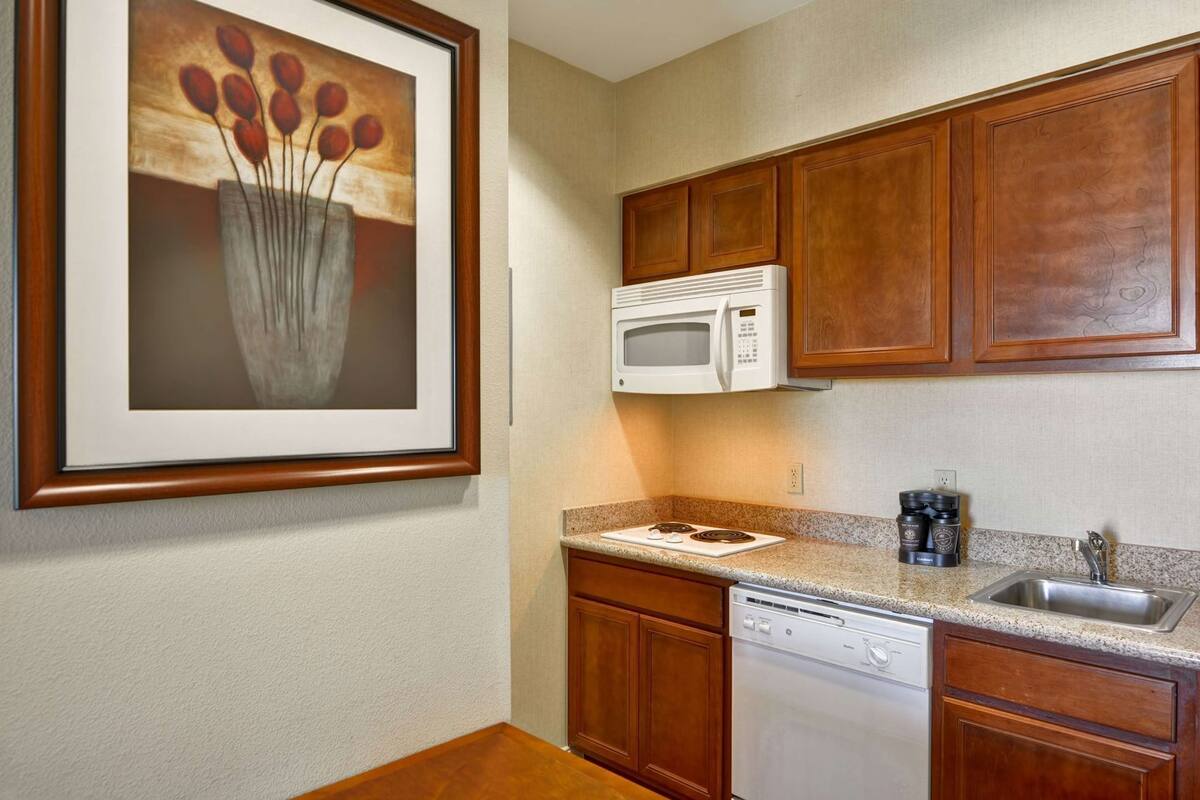 A kitchen with wooden cabinets, a microwave, a stove, and a dishwasher.