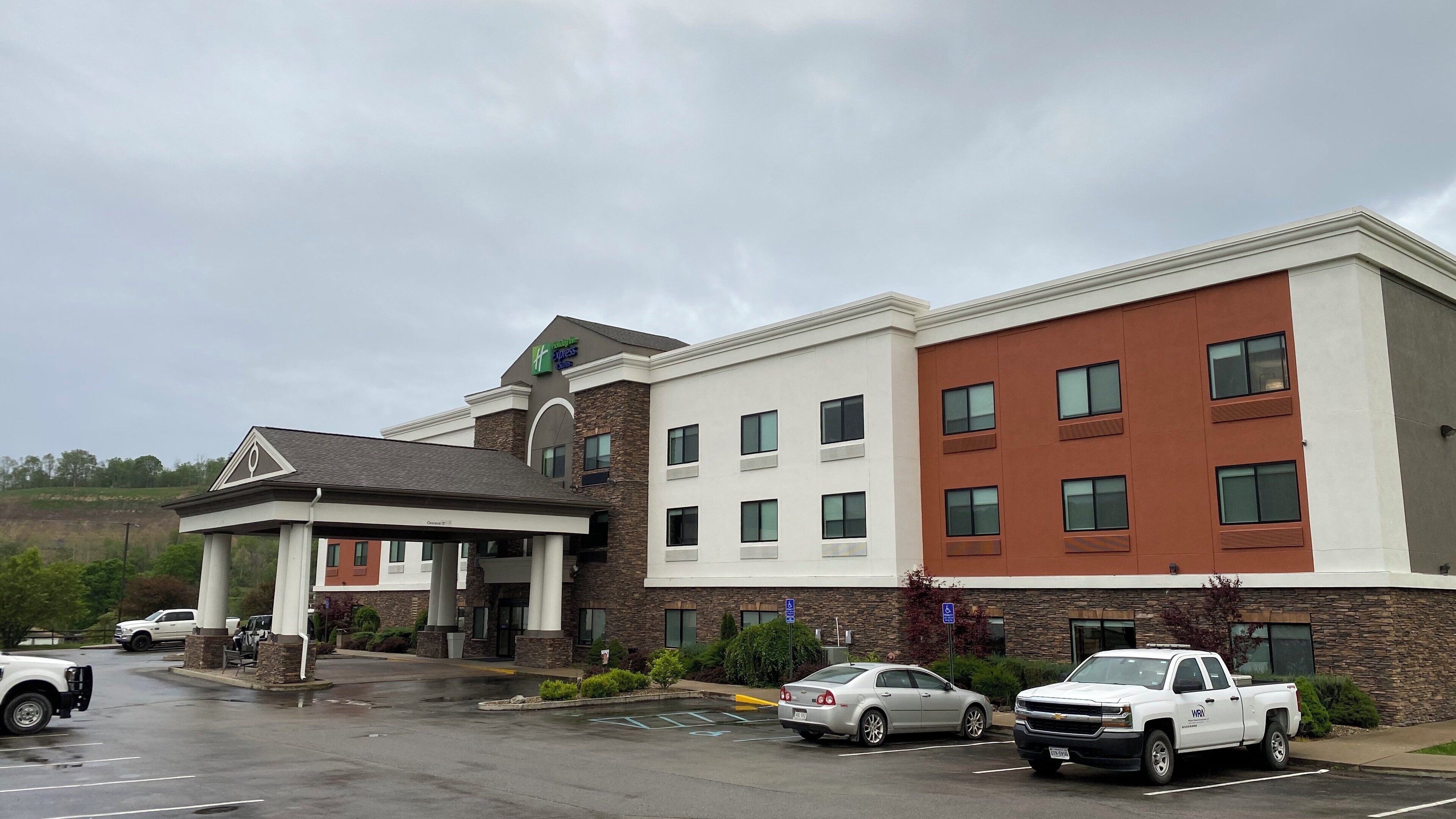 A multi-story hotel with a covered entrance, parking lot, and a sign indicating handicap accessibility.