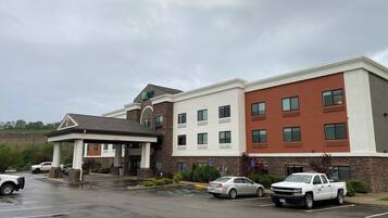 A multi-story hotel with a covered entrance, parking lot, and a sign indicating handicap accessibility.