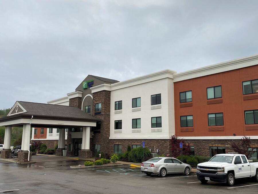 A multi-story hotel with a covered entrance, parking lot, and a sign indicating handicap accessibility.