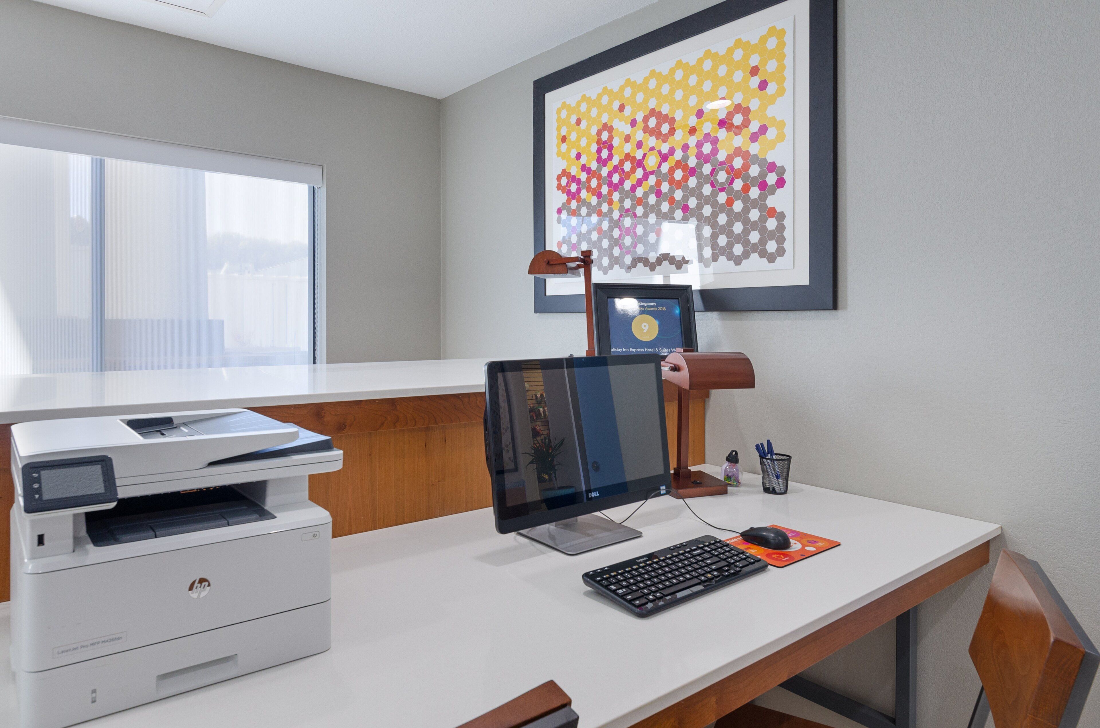 A hotel office with a desk, computer, printer, and framed award.