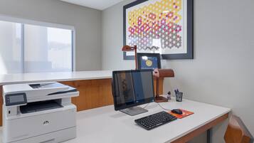 A hotel office with a desk, computer, printer, and framed award.