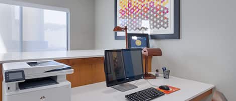 A hotel office with a desk, computer, printer, and framed award.