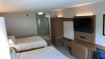 A hotel room with two beds, a desk, a television, and a wardrobe.