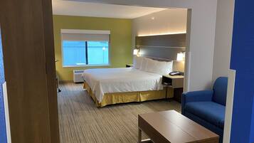 A hotel room with a bed, bedside table, lamp, and a blue chair.
