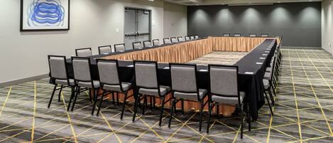 A conference room with a long table, chairs, and a patterned carpet.