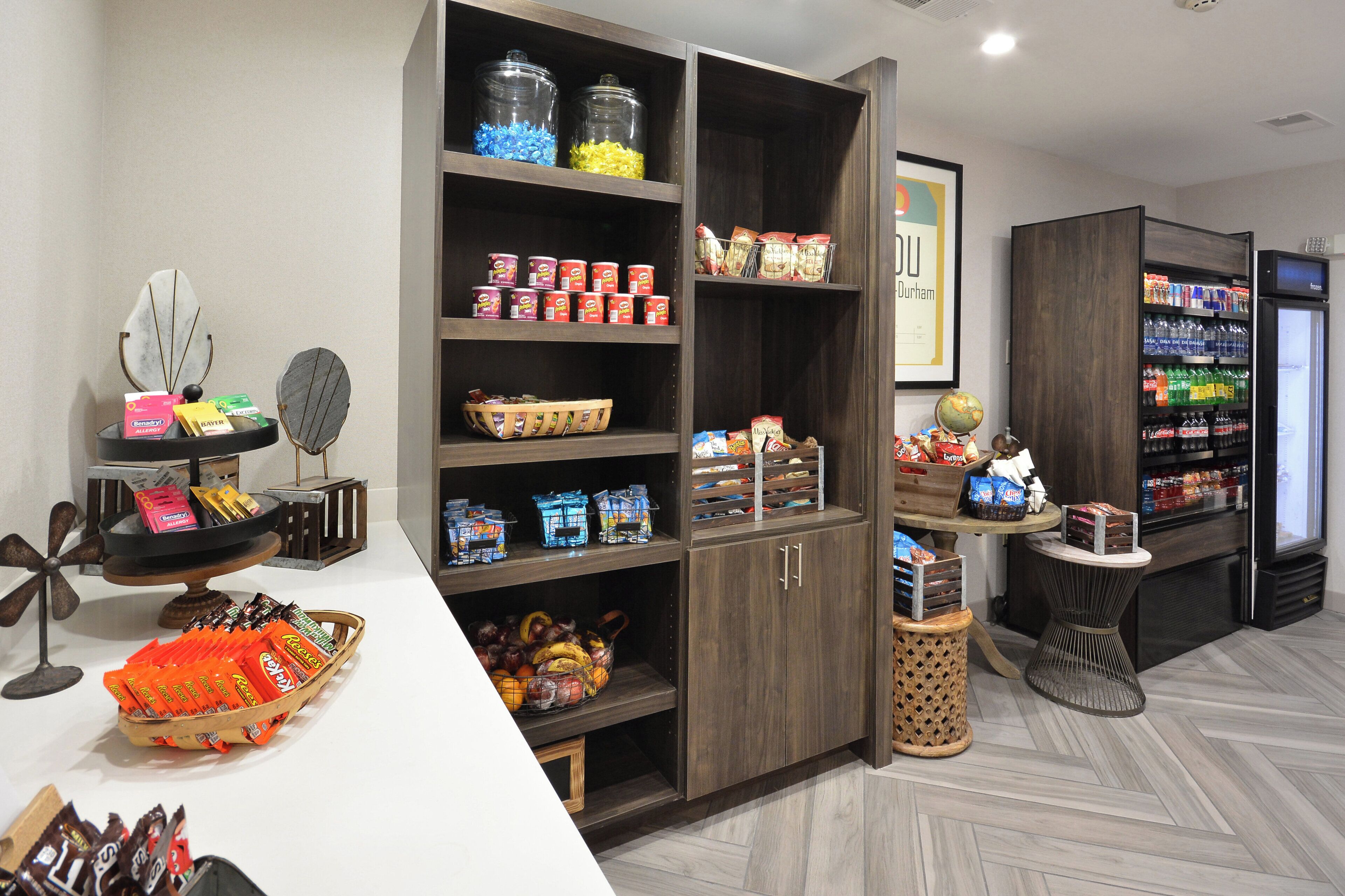 A snack and beverage area with shelves stocked with various snacks, a refrigerator, and a globe on a table.
