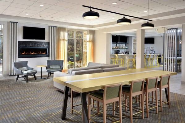 A hotel lobby with a seating area, a bar, and a fireplace.
