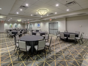 A conference room with multiple tables and chairs, a patterned carpet, and ceiling lights.