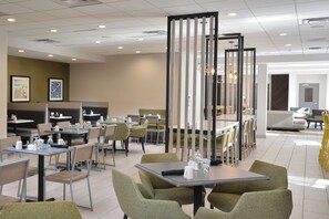 A modern dining area with tables and chairs, a decorative partition, and artwork on the walls.