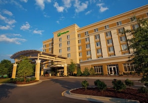 A large hotel with a covered entrance, multiple floors, and a landscaped front yard.