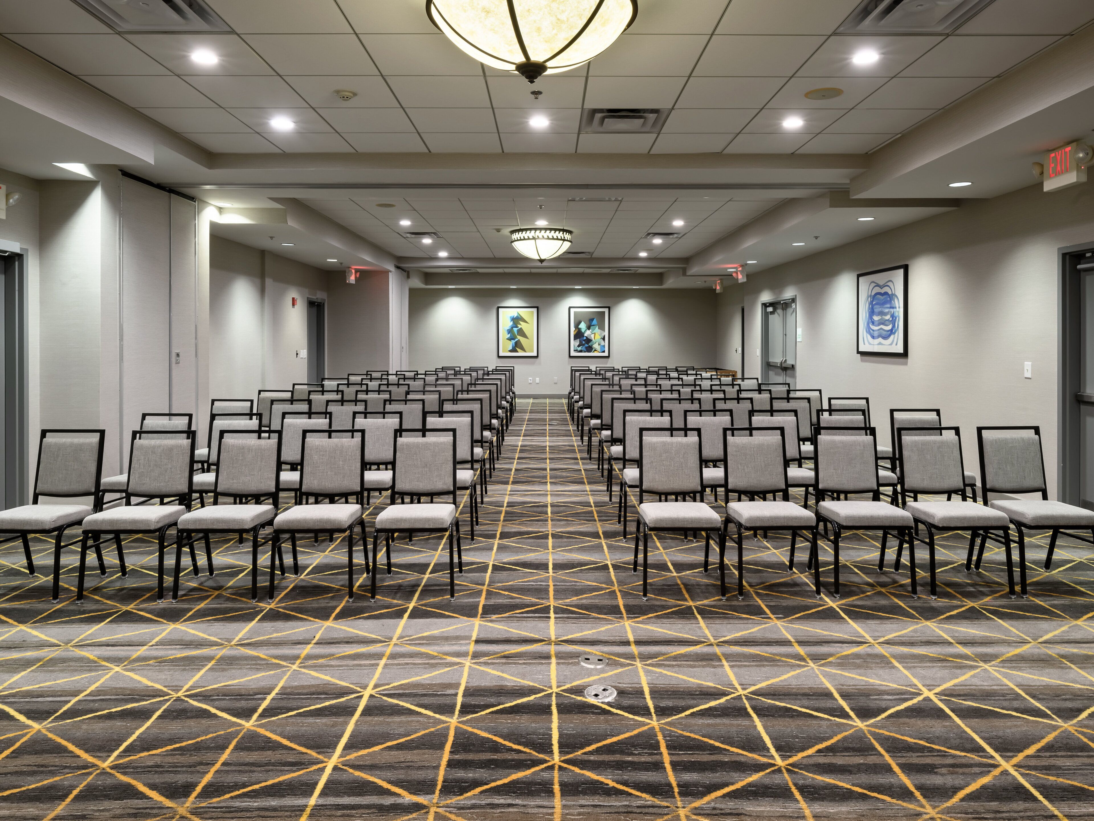 A conference room with rows of chairs, a patterned carpet, and a chandelier.