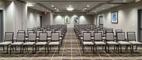 A conference room with rows of chairs, a patterned carpet, and a chandelier.