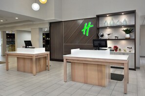 A modern reception area with two reception desks, a large illuminated sign, and a decorative wall with shelves.