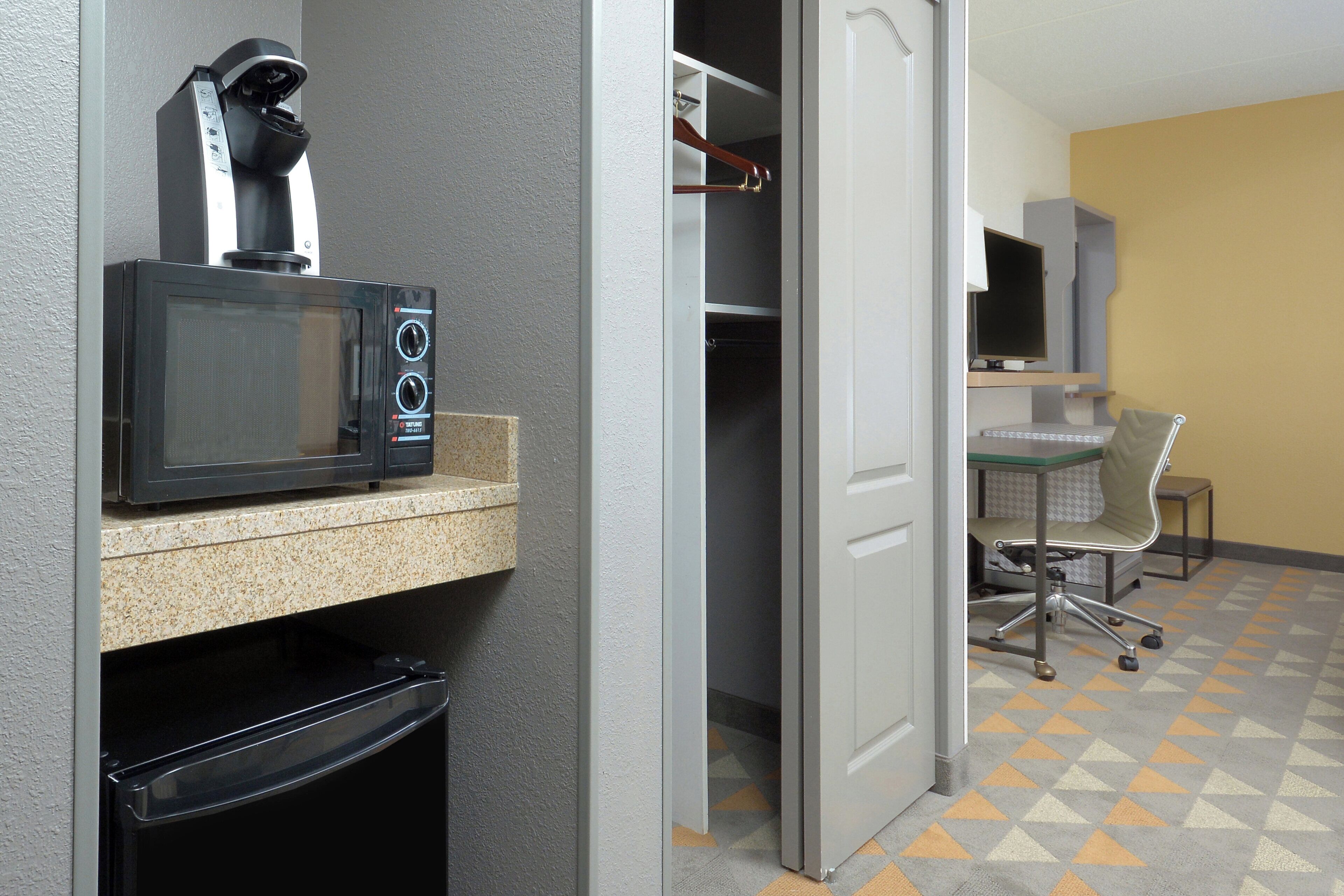 A kitchenette with a microwave, a coffee maker, and a trash bin.