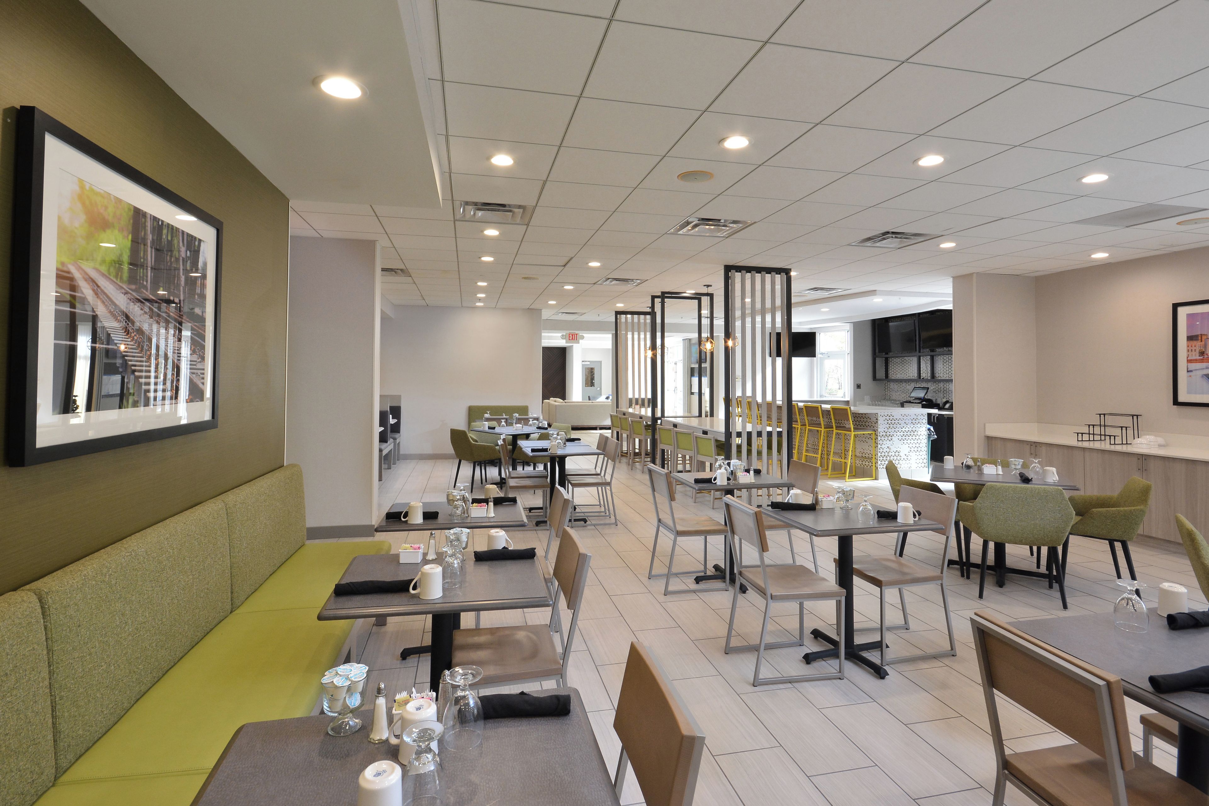A modern dining area with tables and chairs, a kitchen area, and a framed picture on the wall.