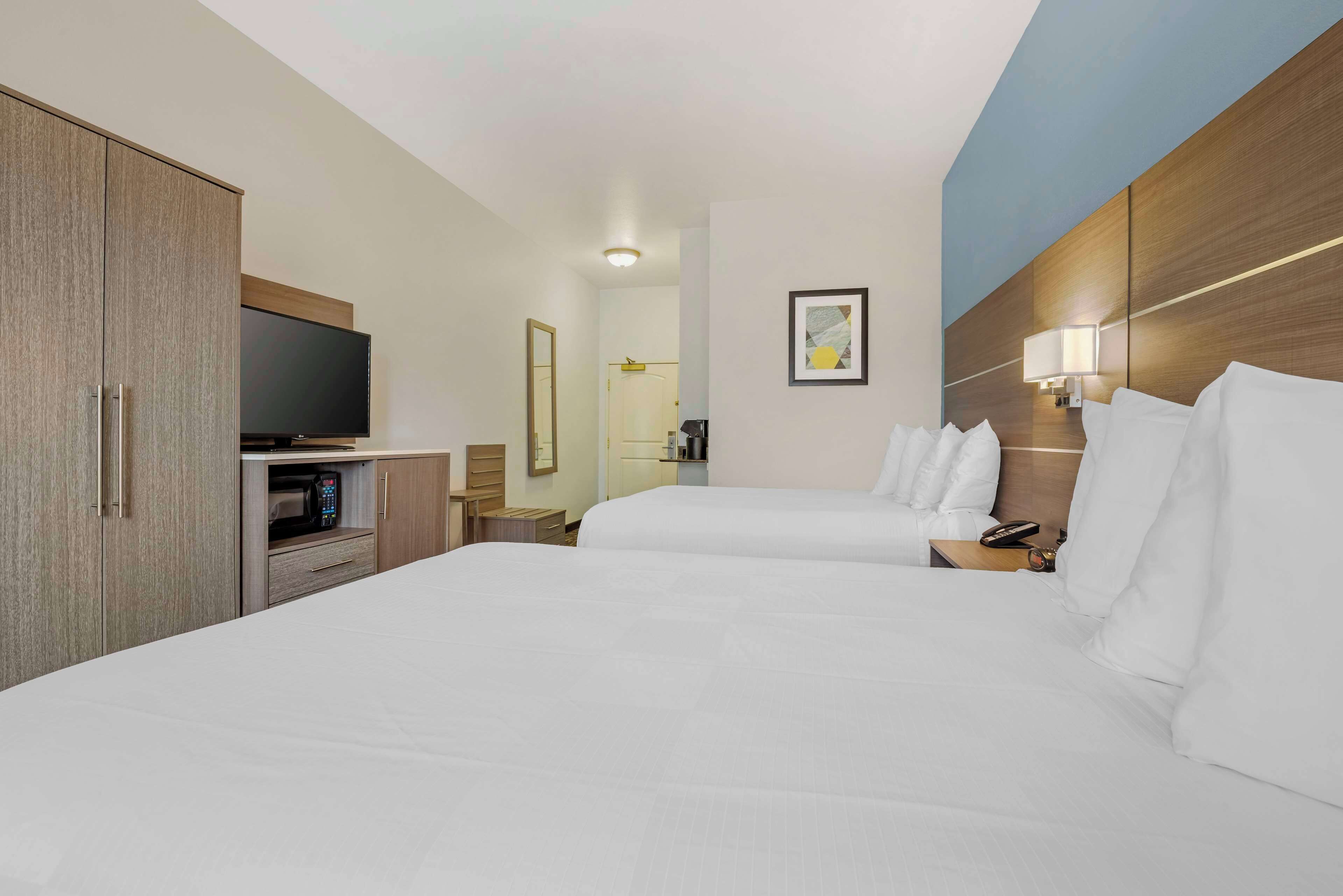 Una habitación de hotel con dos camas, televisión, cafetera y espejo.